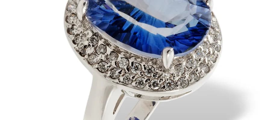A white metal ring set with a large oval stone inside a border of small brilliants.