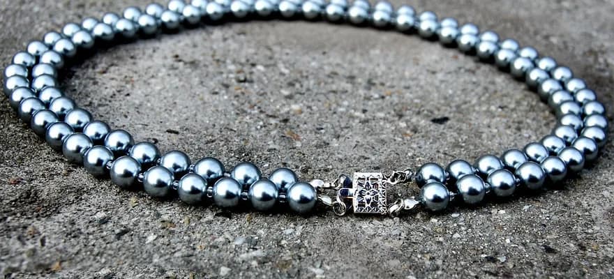 A strand of round pearls laid out on a stone surface.